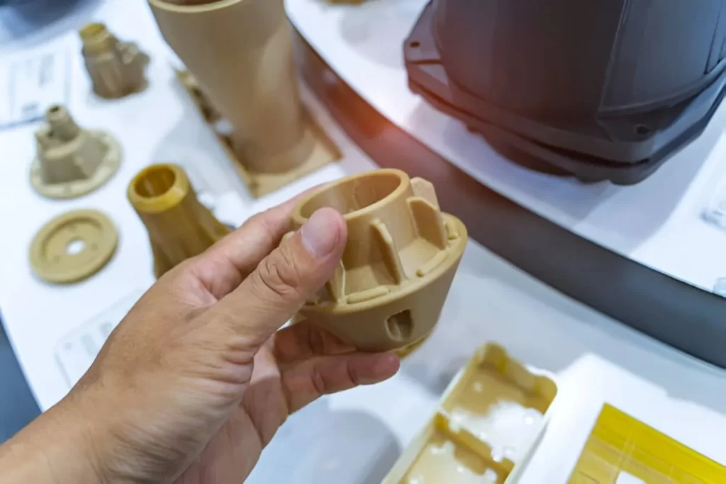一人手持并展示几个PEEK注塑成型的航空航天零件。