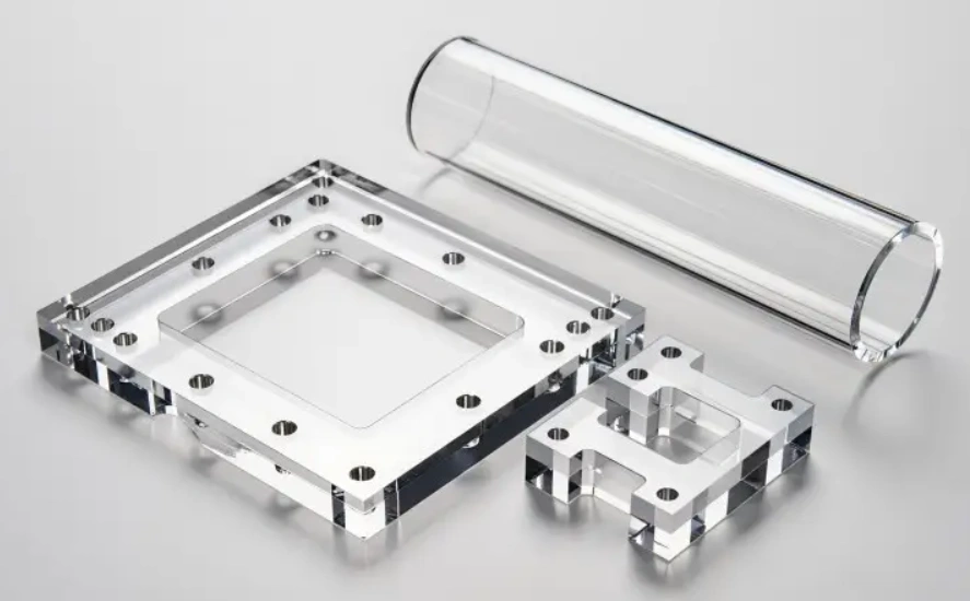 CNC-gefreesde onderdelen van transparant acryl, waaronder een vierkant frame, een beugel en een holle buis.