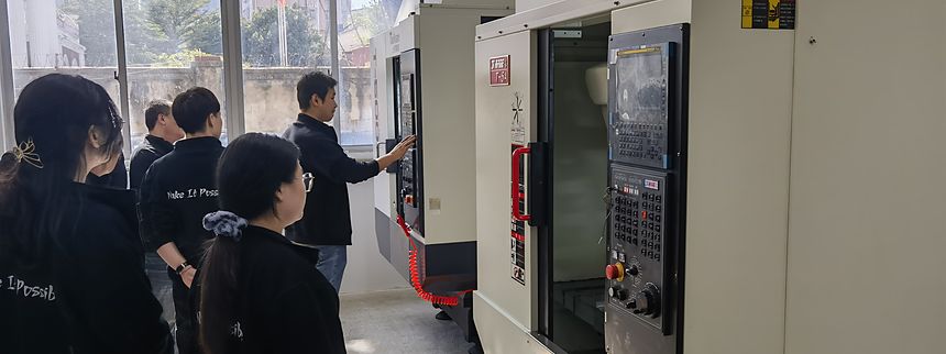 Menschen hatten sich am Bedienfeld eines CNC-Bearbeitungszentrums in der Werkstatt versammelt.