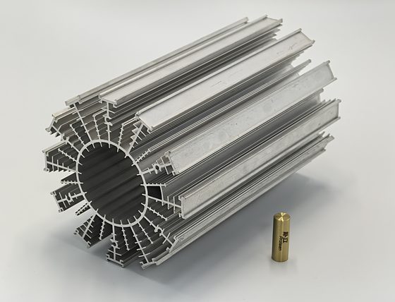 Ein gefräster Aluminium-Kühlkörper mit Stiftrippen, neben einem kleinen gefrästen Messinganschluss